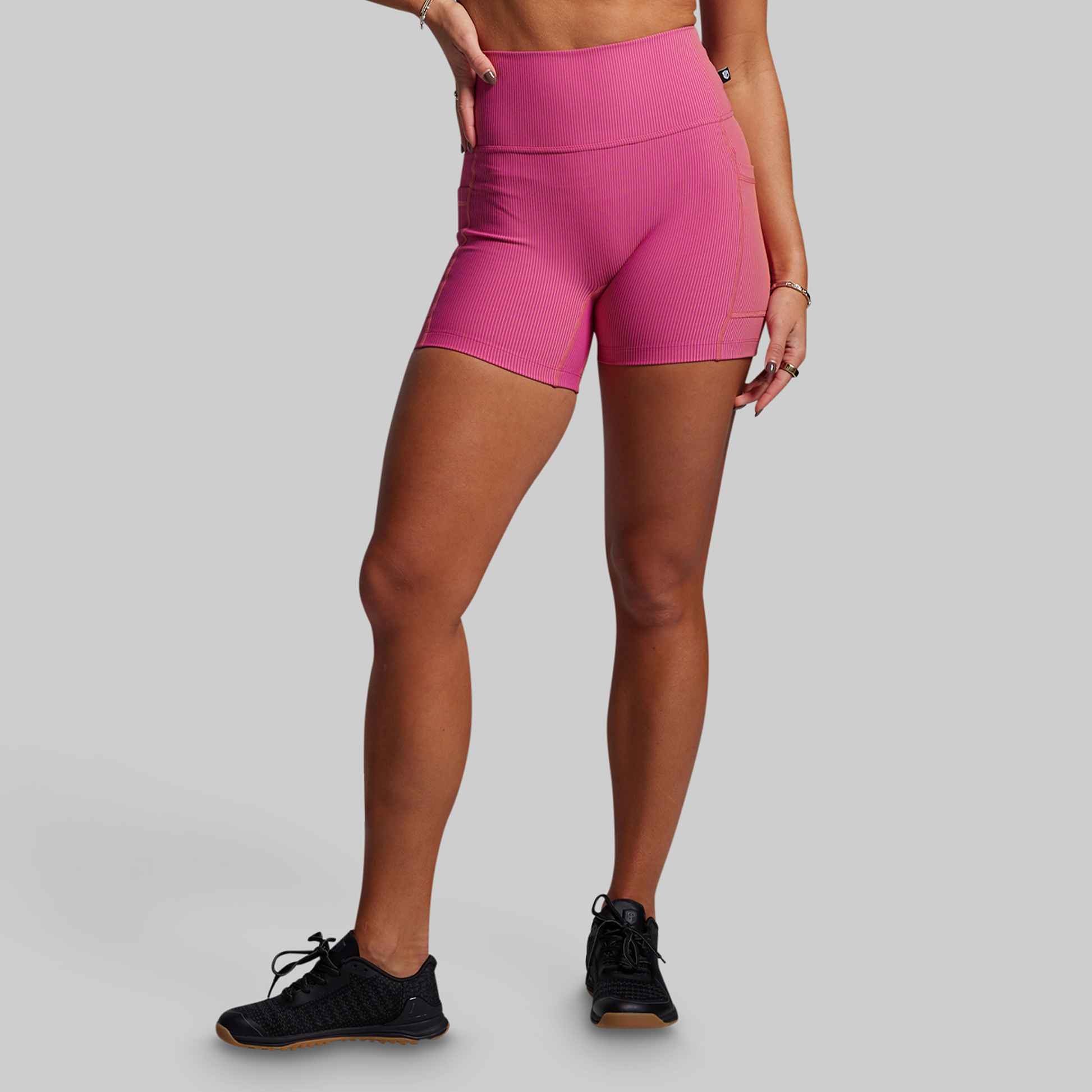 Person wearing pink ribbed athletic shorts on a gray background
