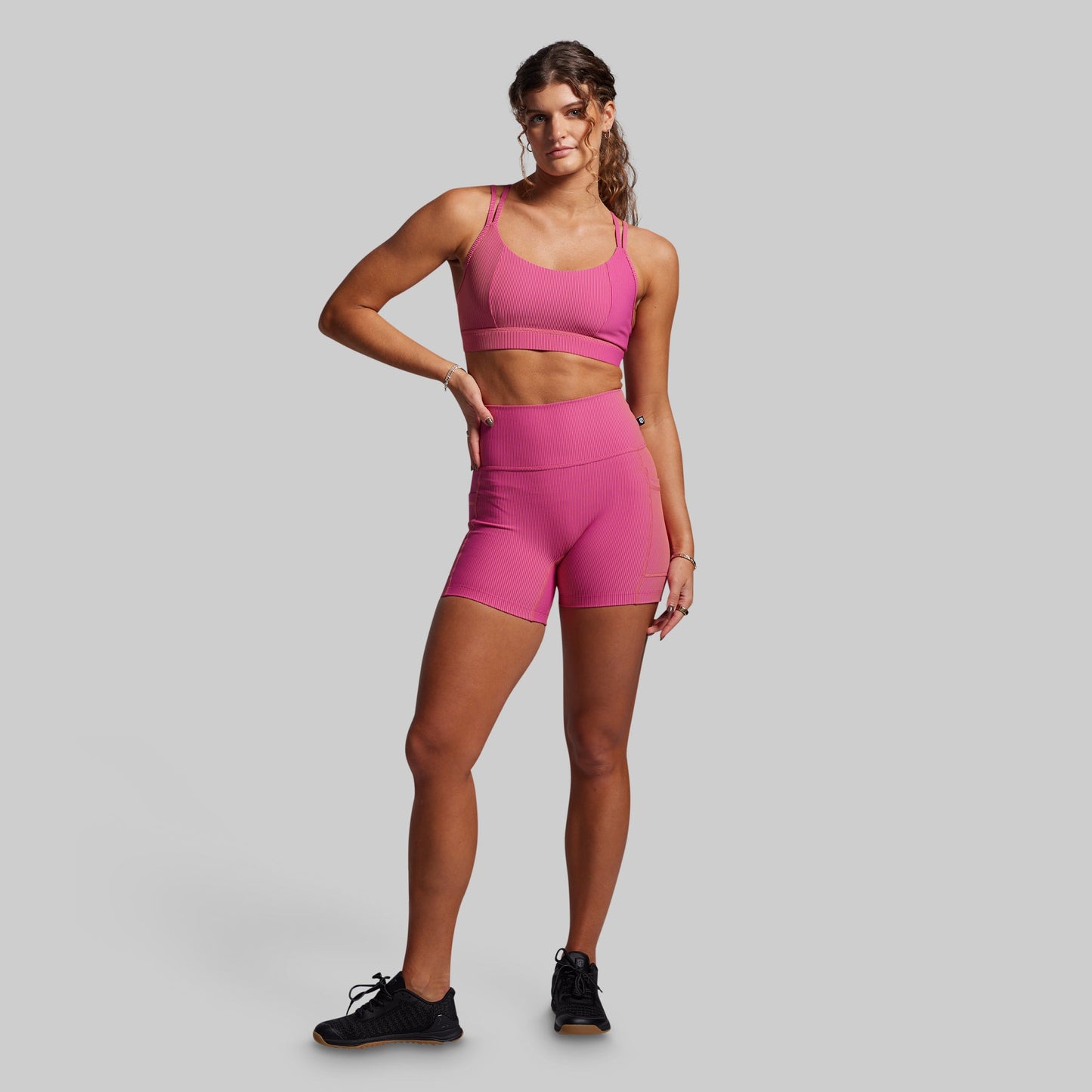 Women wearing pink ribbed athletic shorts on a gray background