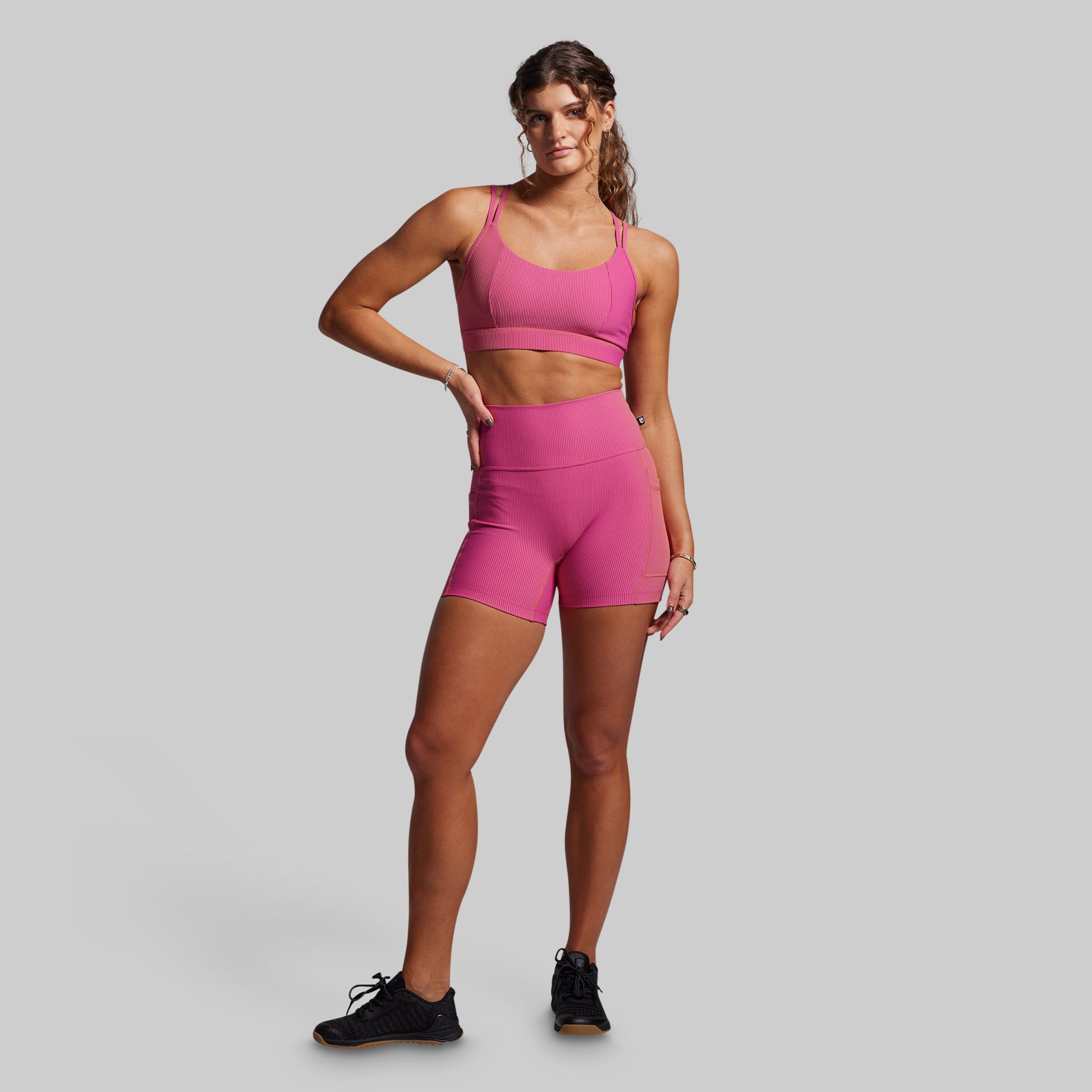 Women wearing pink ribbed athletic shorts on a gray background