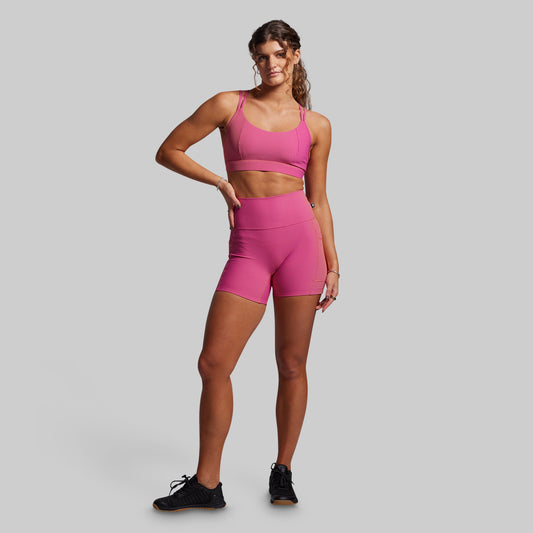 Woman wearing a pink ribbed athletic outfit on a gray background
