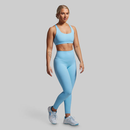 Woman wearing a light blue athletic outfit on a gray background