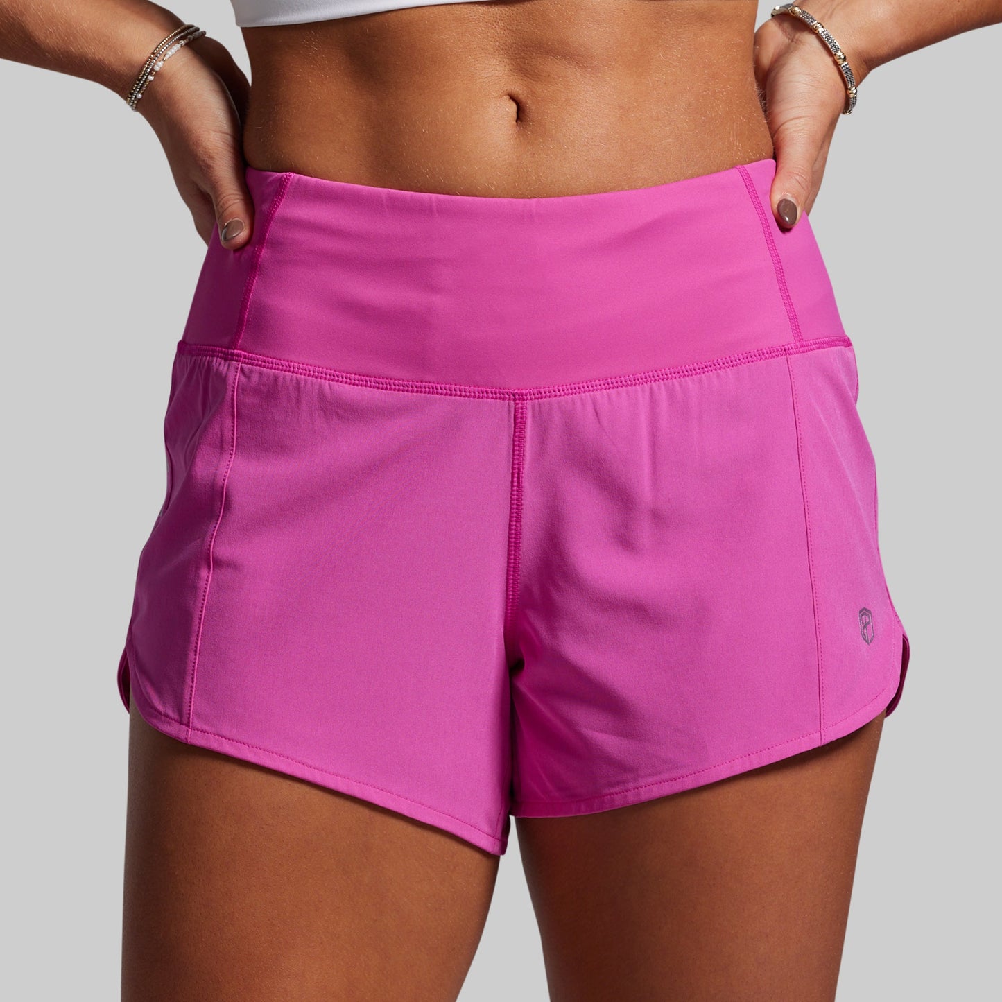 Person wearing bright pink athletic shorts on a plain background