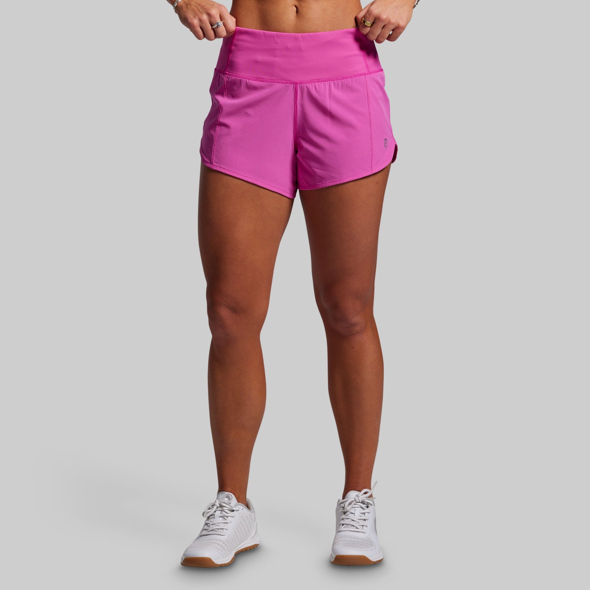 Person wearing bright pink athletic shorts on a gray background