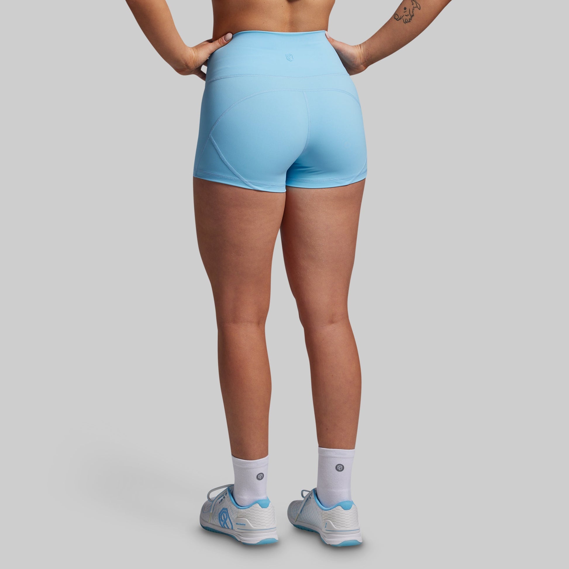 Person wearing light blue athletic shorts on a gray background