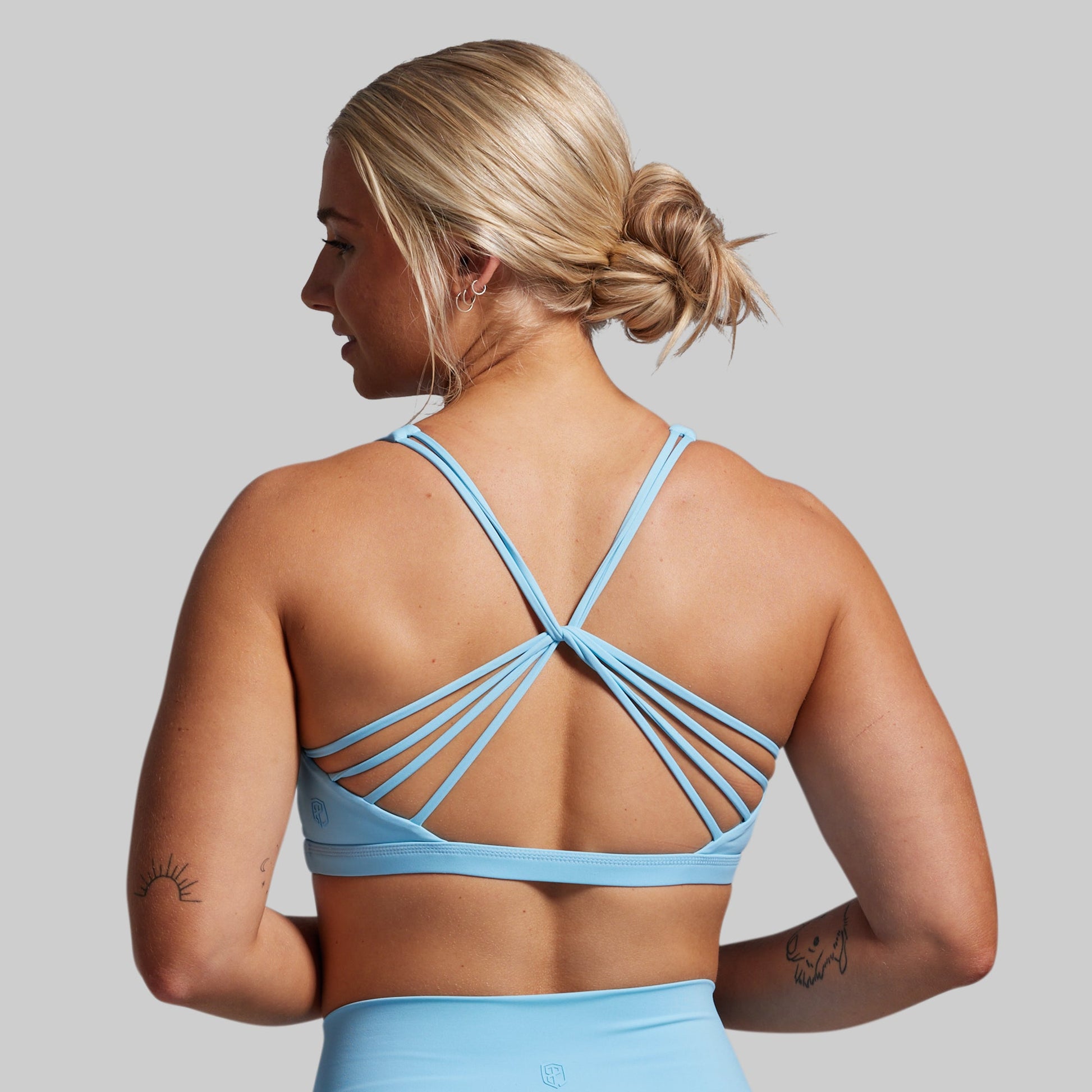Woman wearing a light blue sports bra and leggings against a gray background
