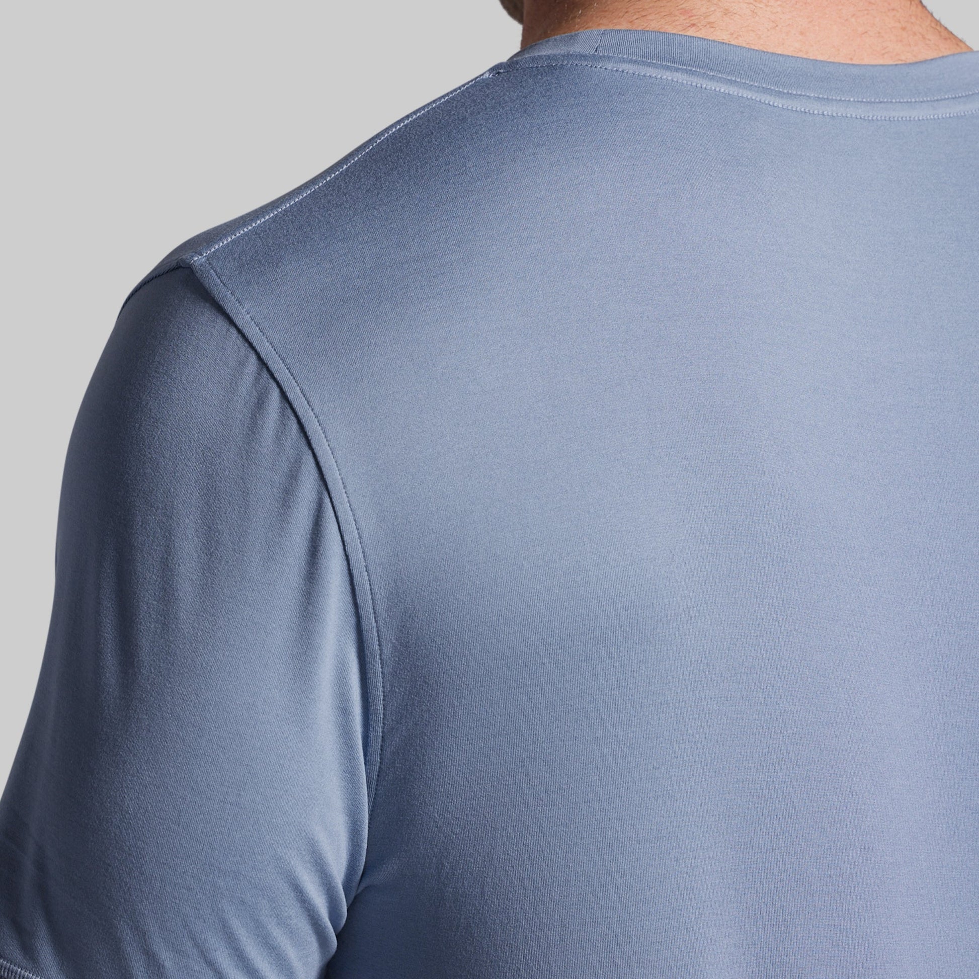 Close-up of a person wearing a light blue athletic shirt on a gray background
