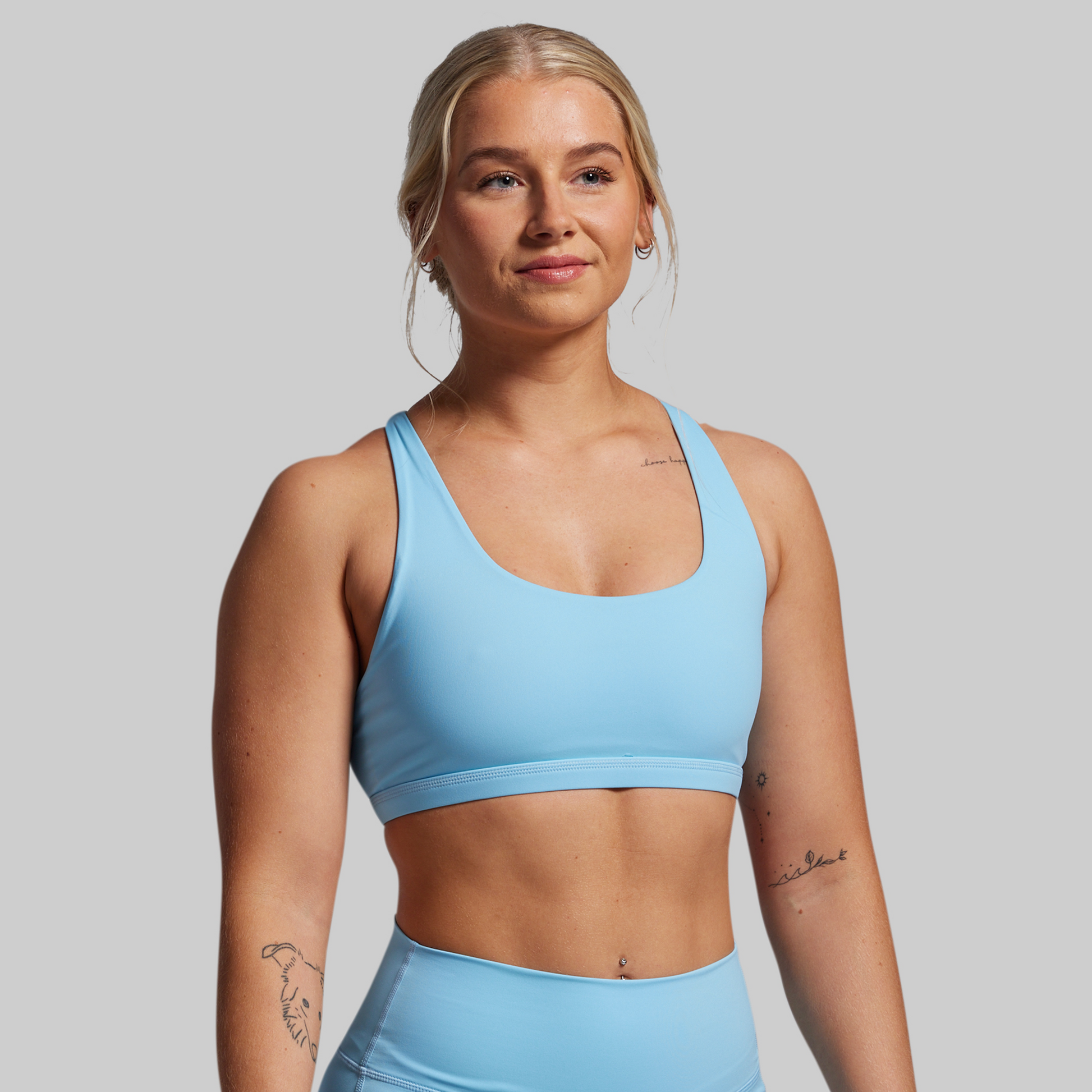 Woman wearing a light blue sports bra and leggings on a gray background