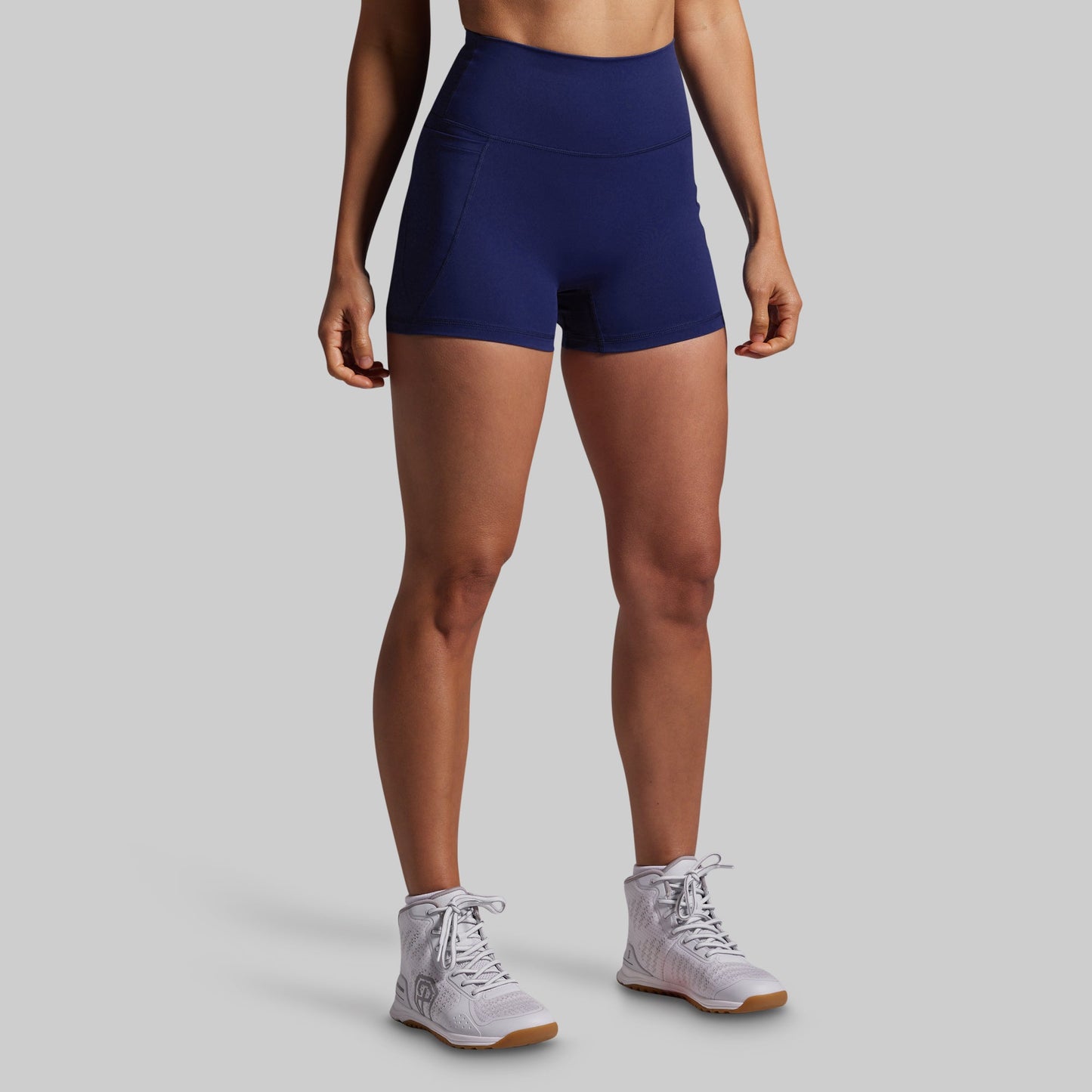 Person wearing navy blue athletic shorts on a gray background