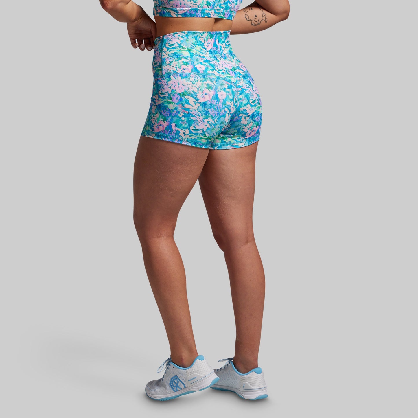 Person wearing a colorful floral sports outfit on a gray background