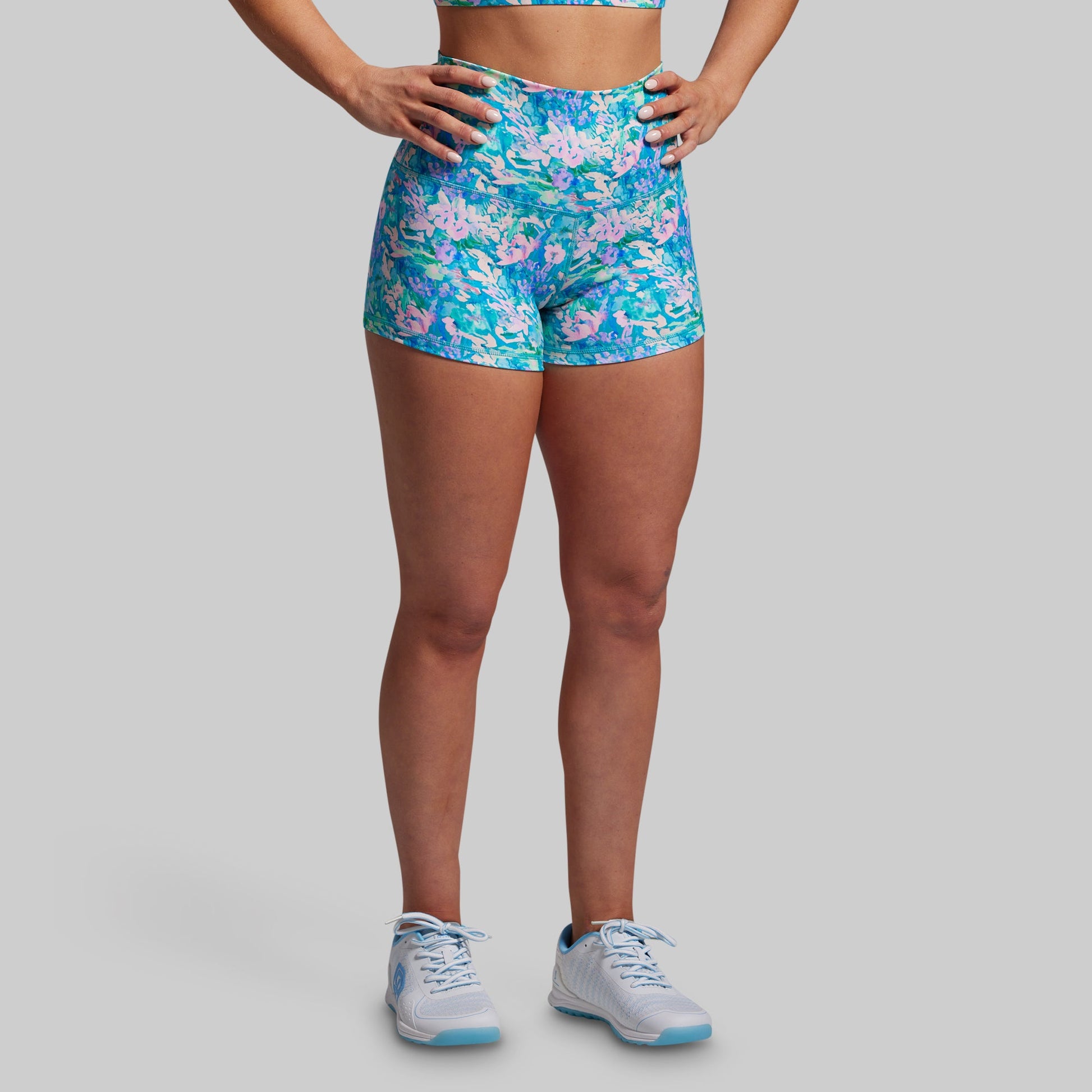Person wearing blue floral shorts on a gray background