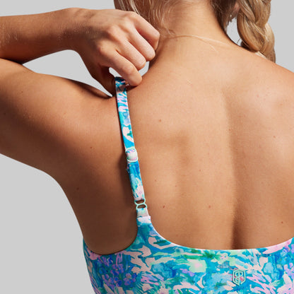 Close-up of a person wearing a colorful sports bra with an adjustable strap on a neutral background