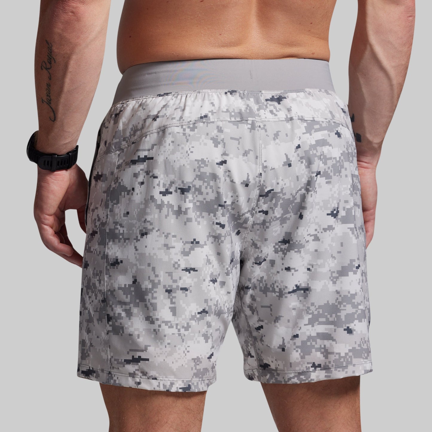 Person wearing camouflage shorts on a plain background