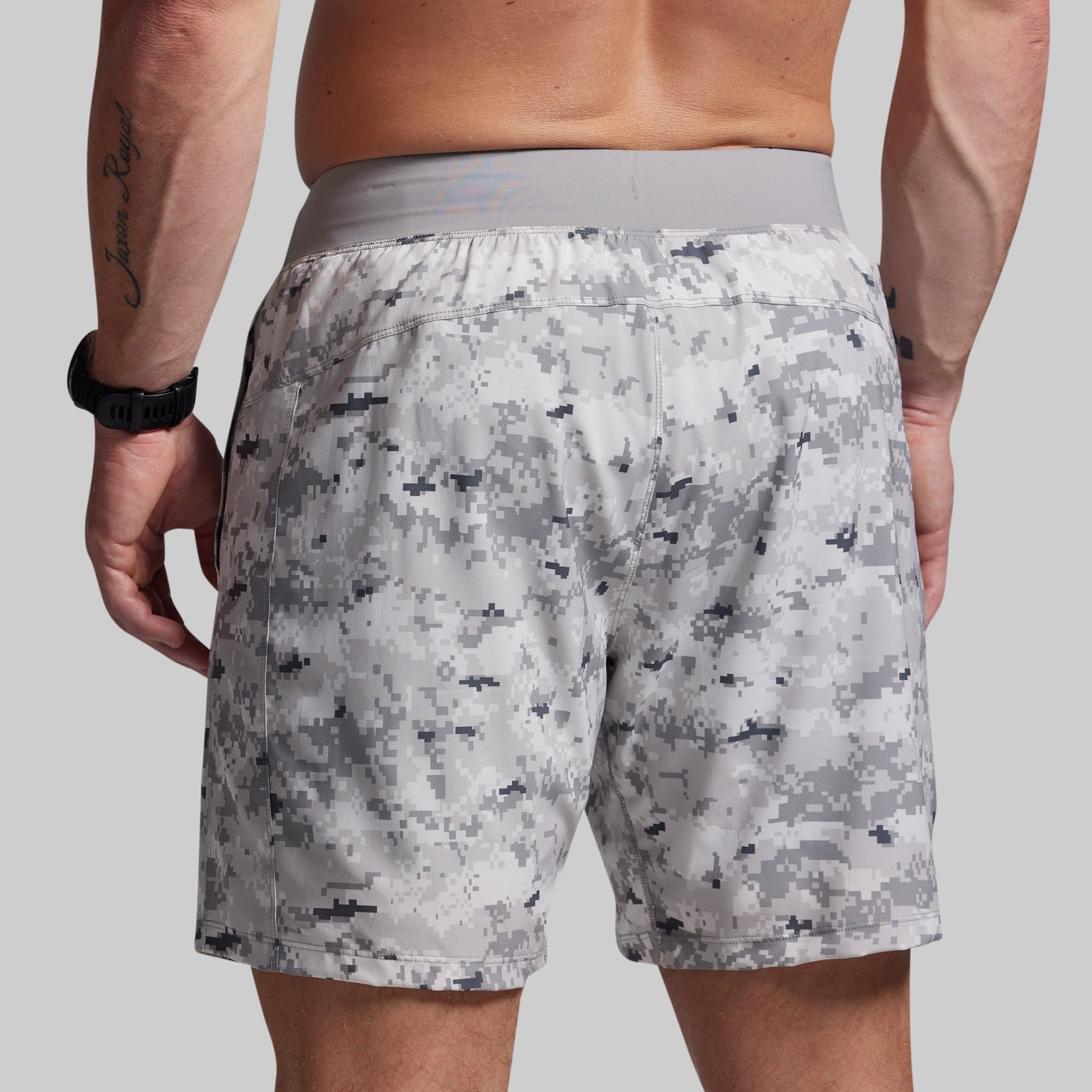 Person wearing camouflage shorts on a plain background