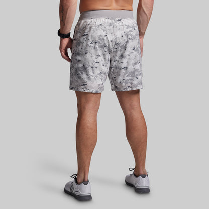 Person wearing camouflage shorts on a plain background