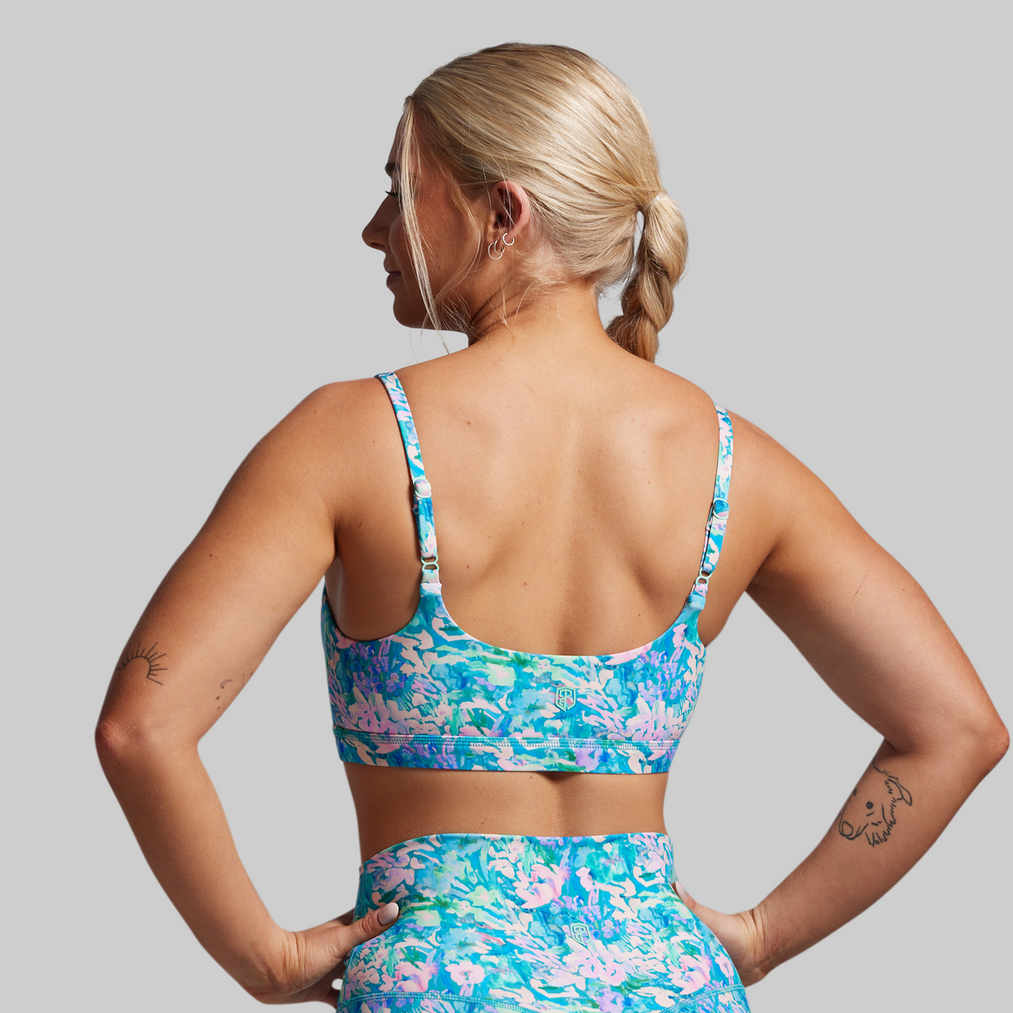 Woman wearing a colorful floral sports bra and shorts set against a gray background