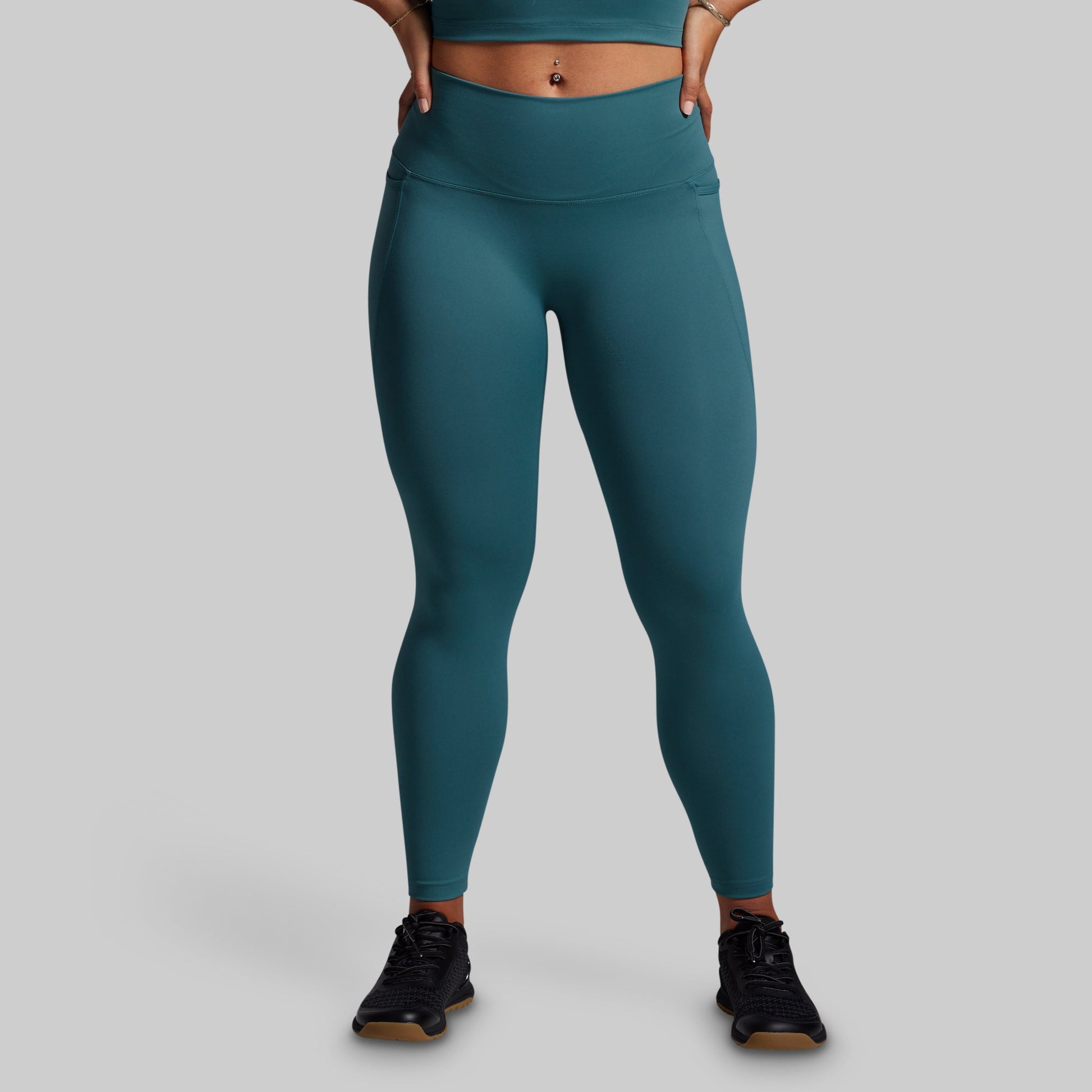 Teal leggings worn by a person on a gray background
