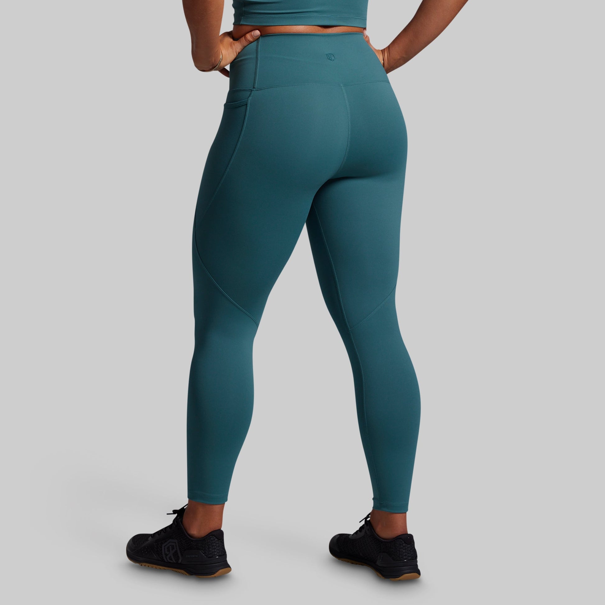 Teal leggings worn by a person on a gray background