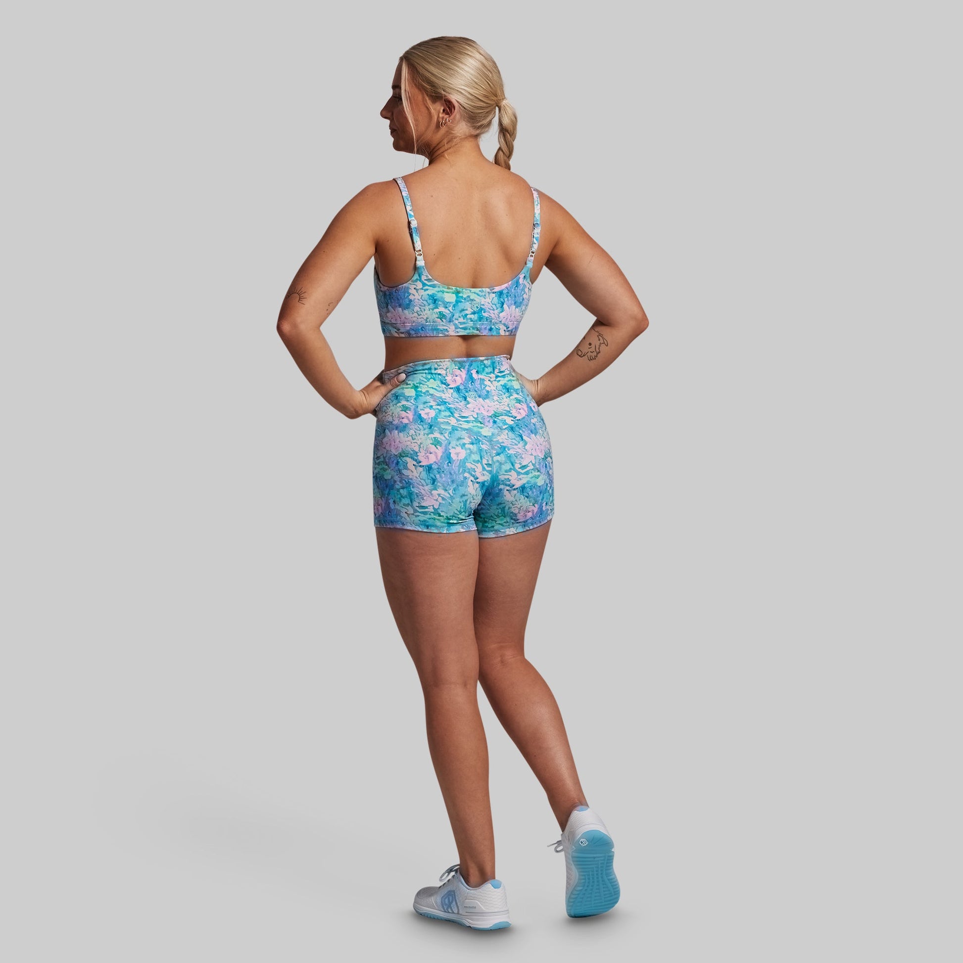 Woman wearing a floral sports bra and shorts set on a gray background