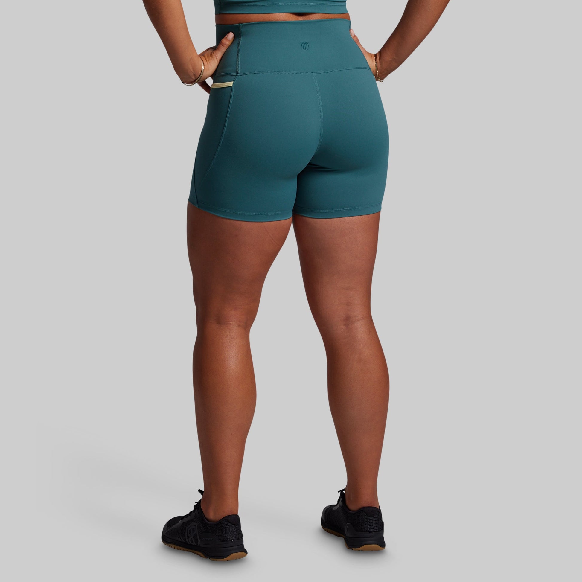 Teal athletic shorts worn by a person on a gray background