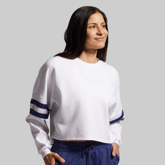 Woman wearing a white sweatshirt with blue accents on a gray background