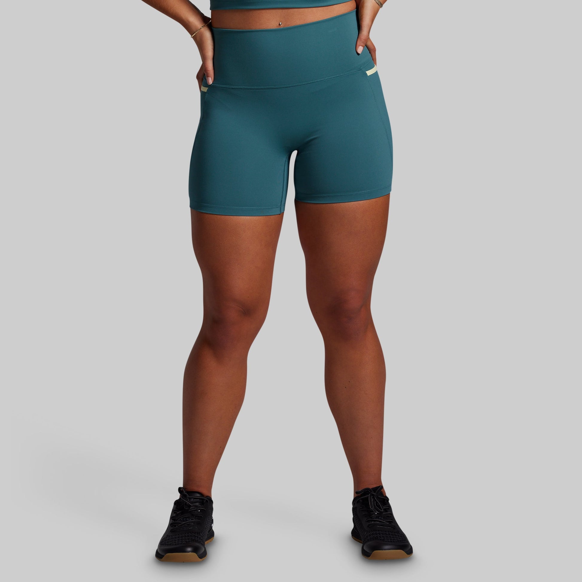 Teal athletic shorts worn by a person on a gray background
