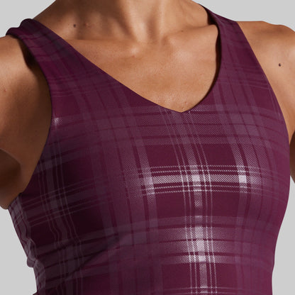 Close-up of a person wearing a sleeveless athletic sports bra with a deep V-neck and a subtle plaid pattern in deep plum purple and gray.