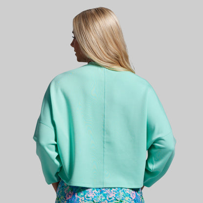 Person wearing a light blue jacket with a plain background