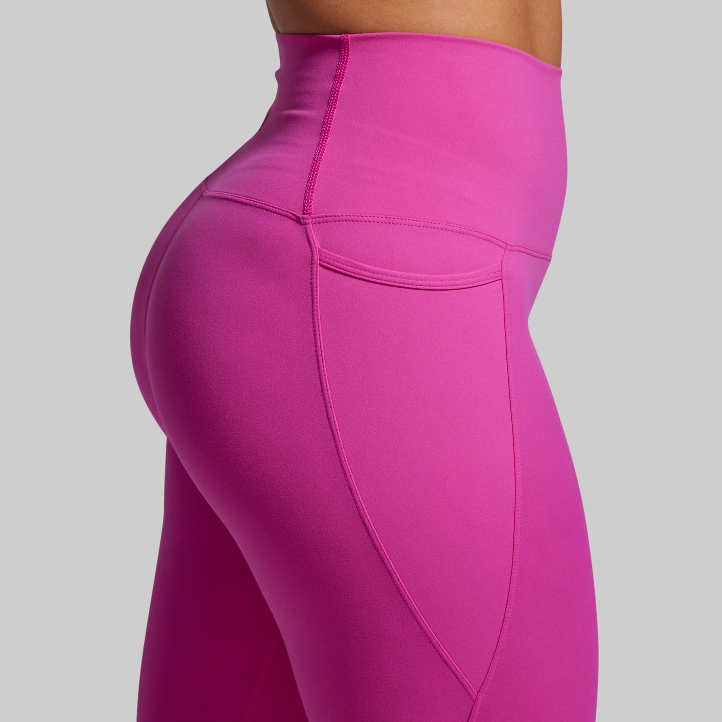 Close-up of the pocket of bright pink leggings on a gray background