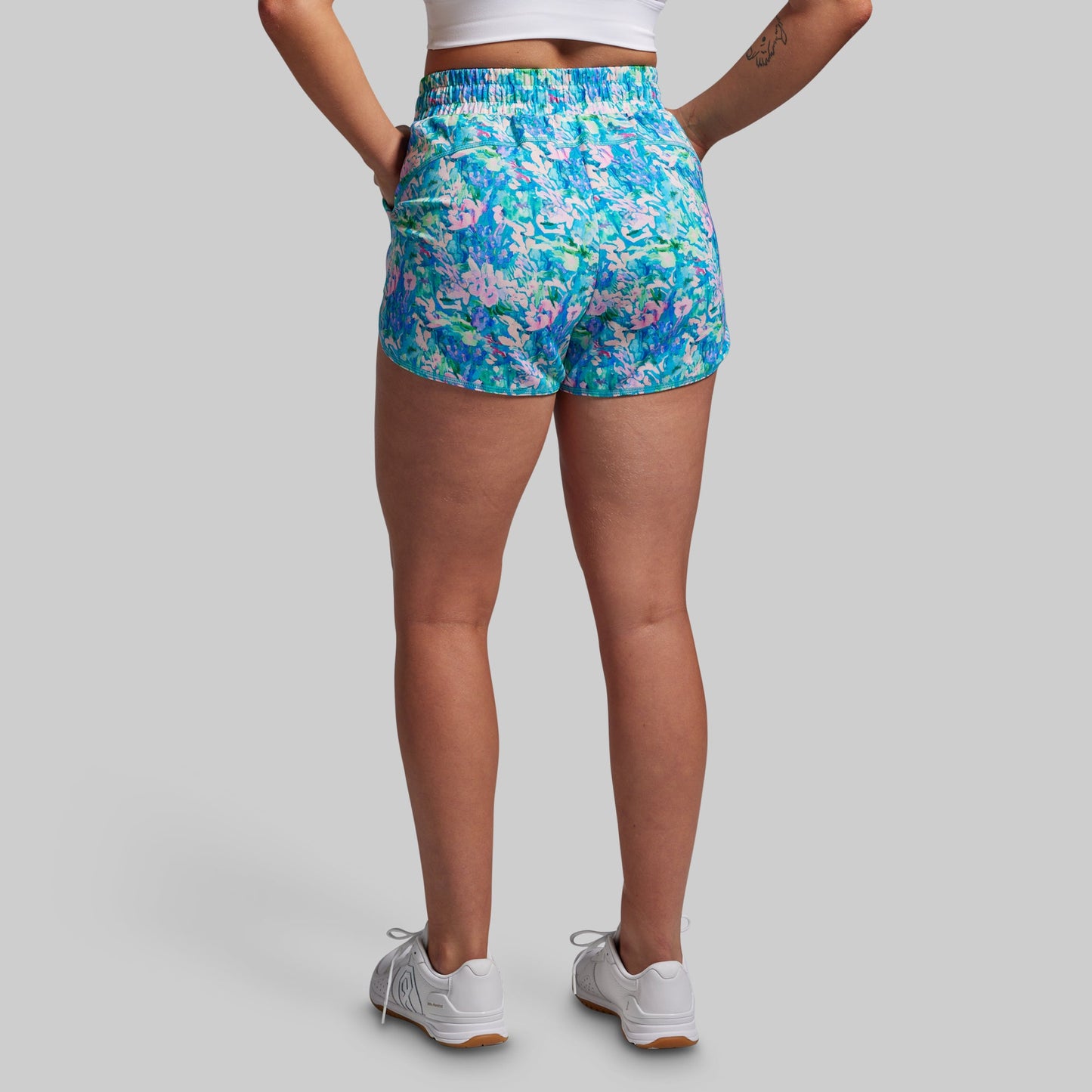 Person wearing colorful floral shorts on a gray background