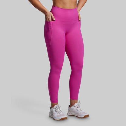 Person wearing bright pink leggings with pockets on a gray background