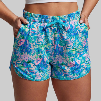 Colorful floral shorts worn by a person on a plain background