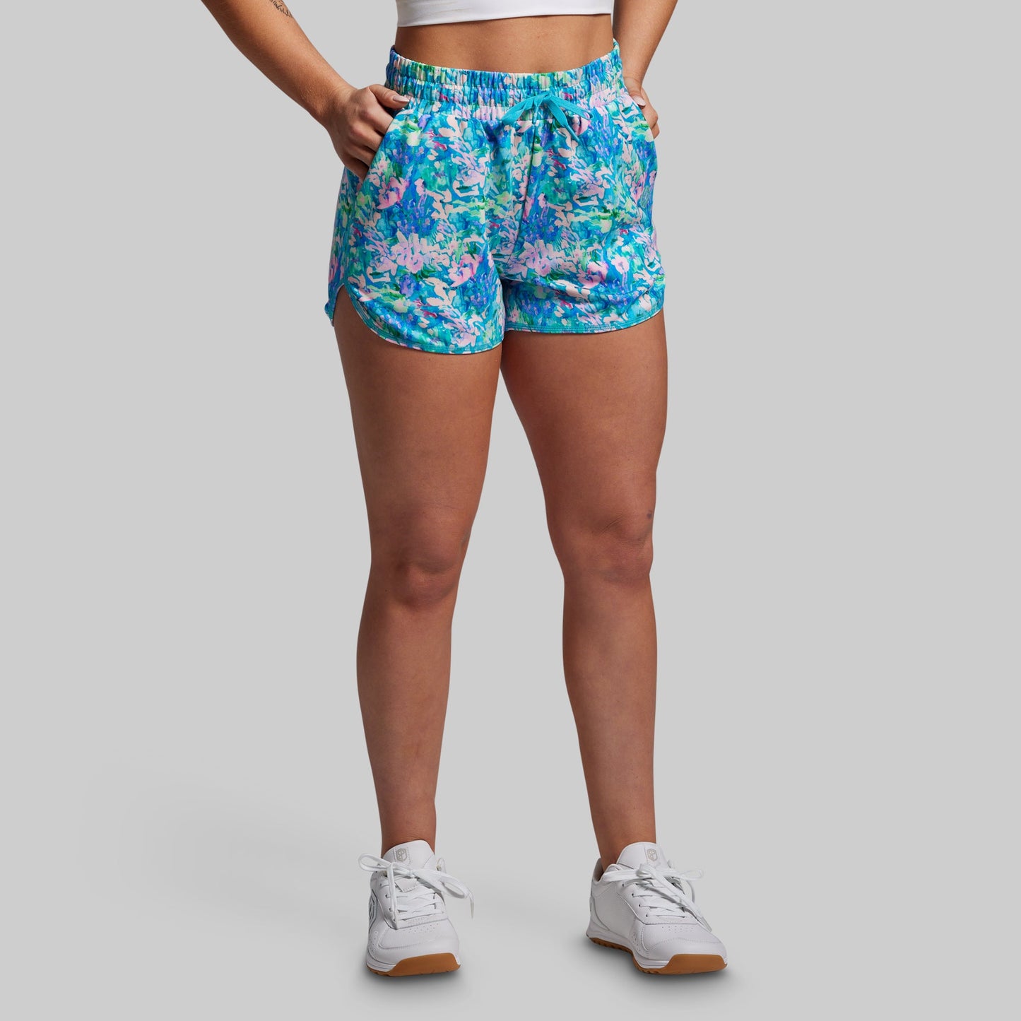 Person wearing colorful floral shorts on a gray background