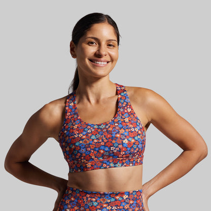 Woman wearing a colorful floral sports bra and leggings on a gray background
