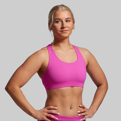 Woman wearing a pink sports bra and shorts on a gray background