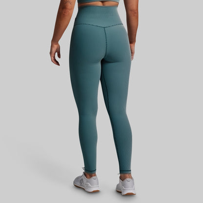 Teal leggings worn by a person on a gray background