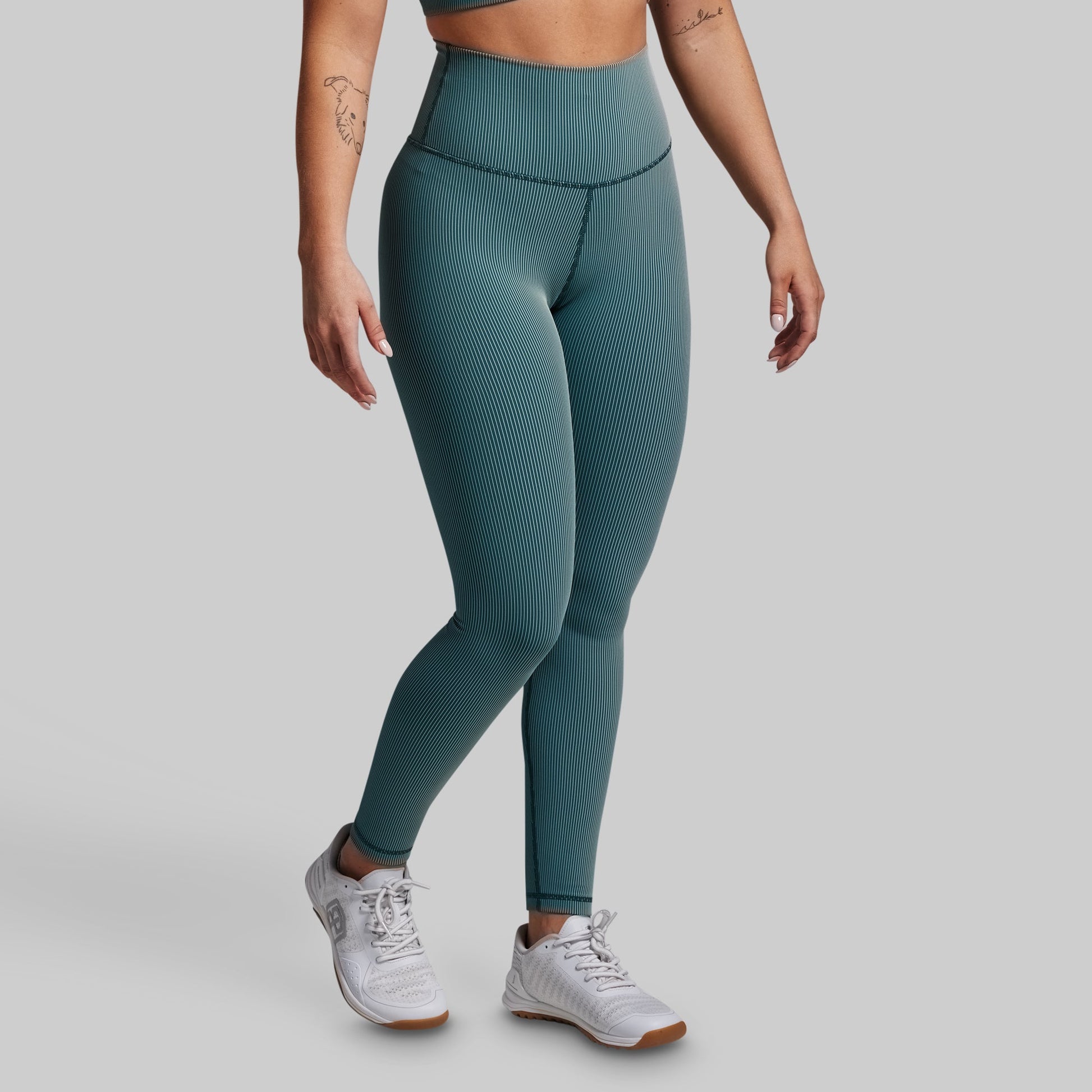 Person wearing teal leggings on a gray background