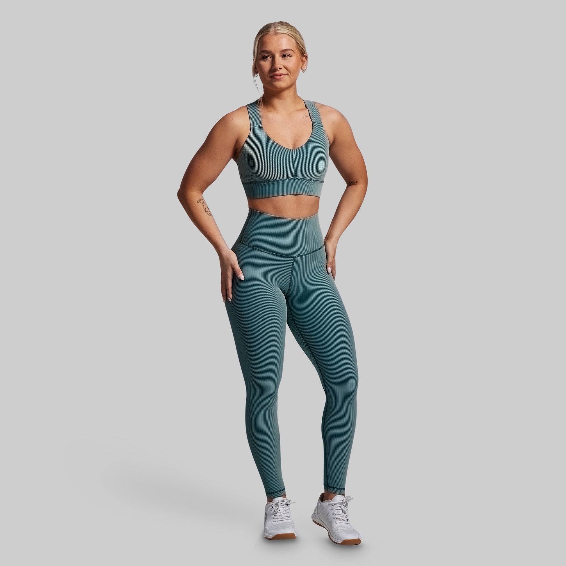 Woman wearing a teal athletic outfit on a gray background