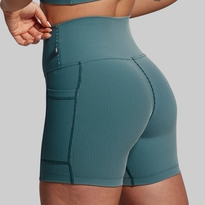 Teal ribbed shorts worn by a person on a gray background