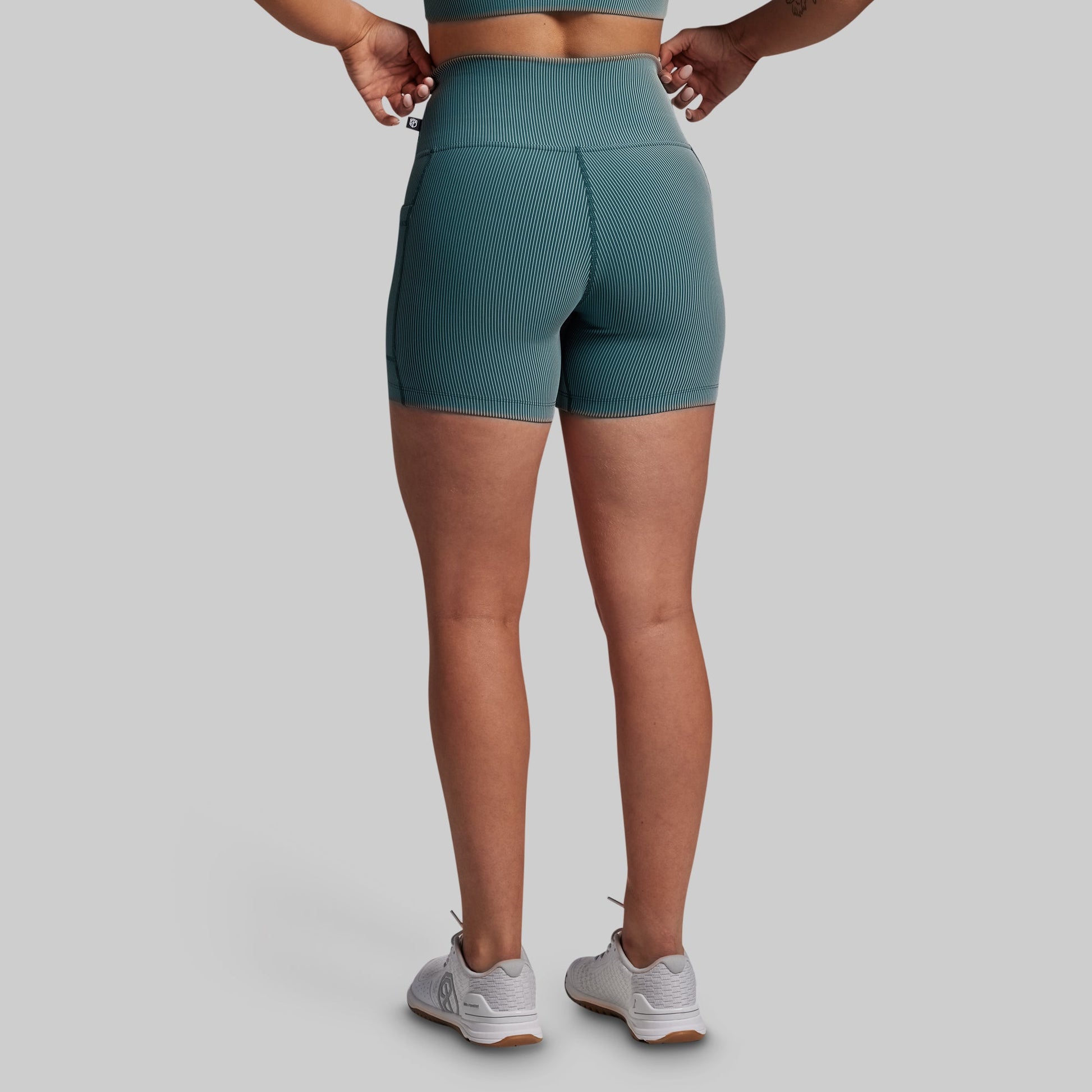 Person wearing teal athletic shorts on a gray background