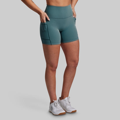Person wearing teal athletic shorts on a gray background