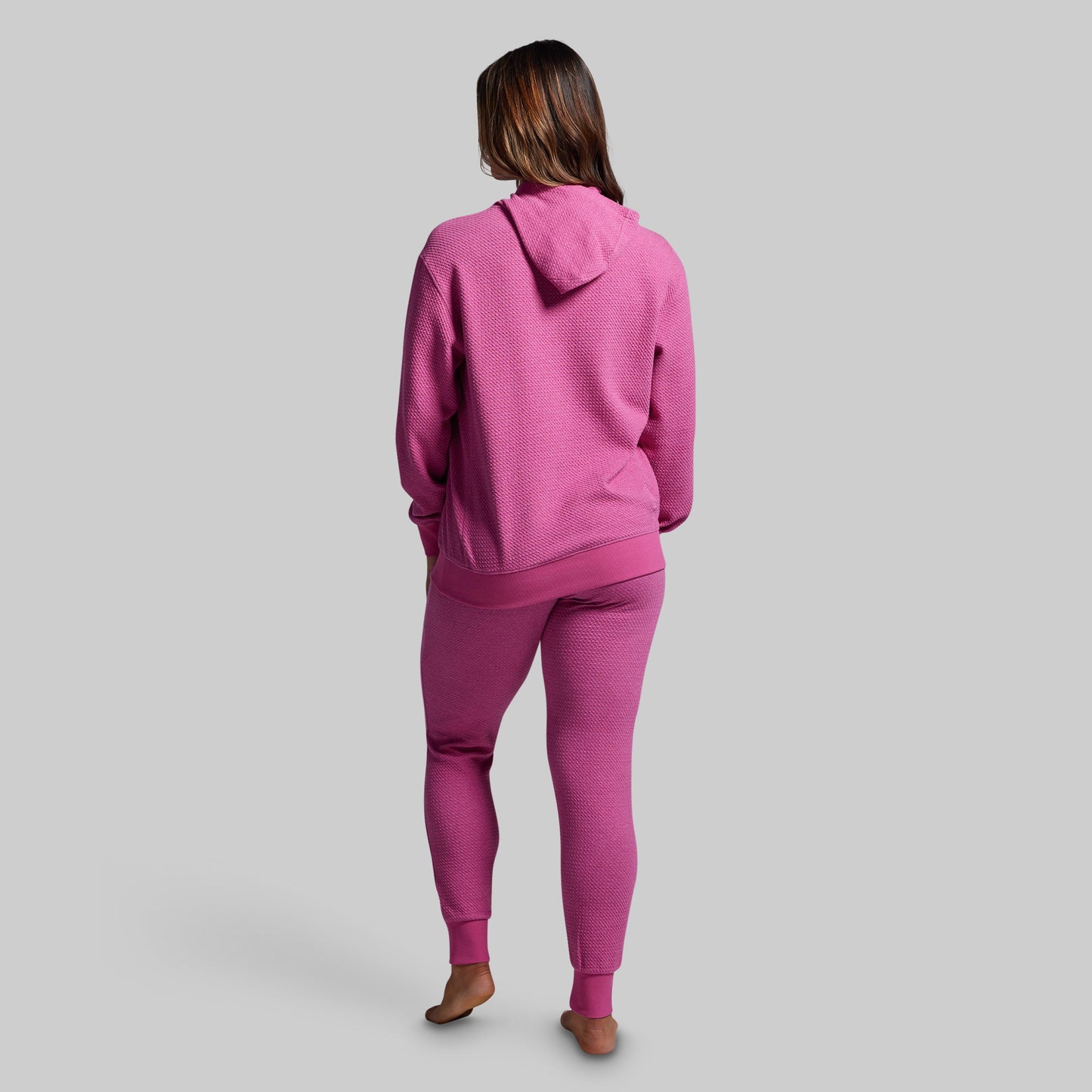 Person wearing a pink tracksuit on a gray background