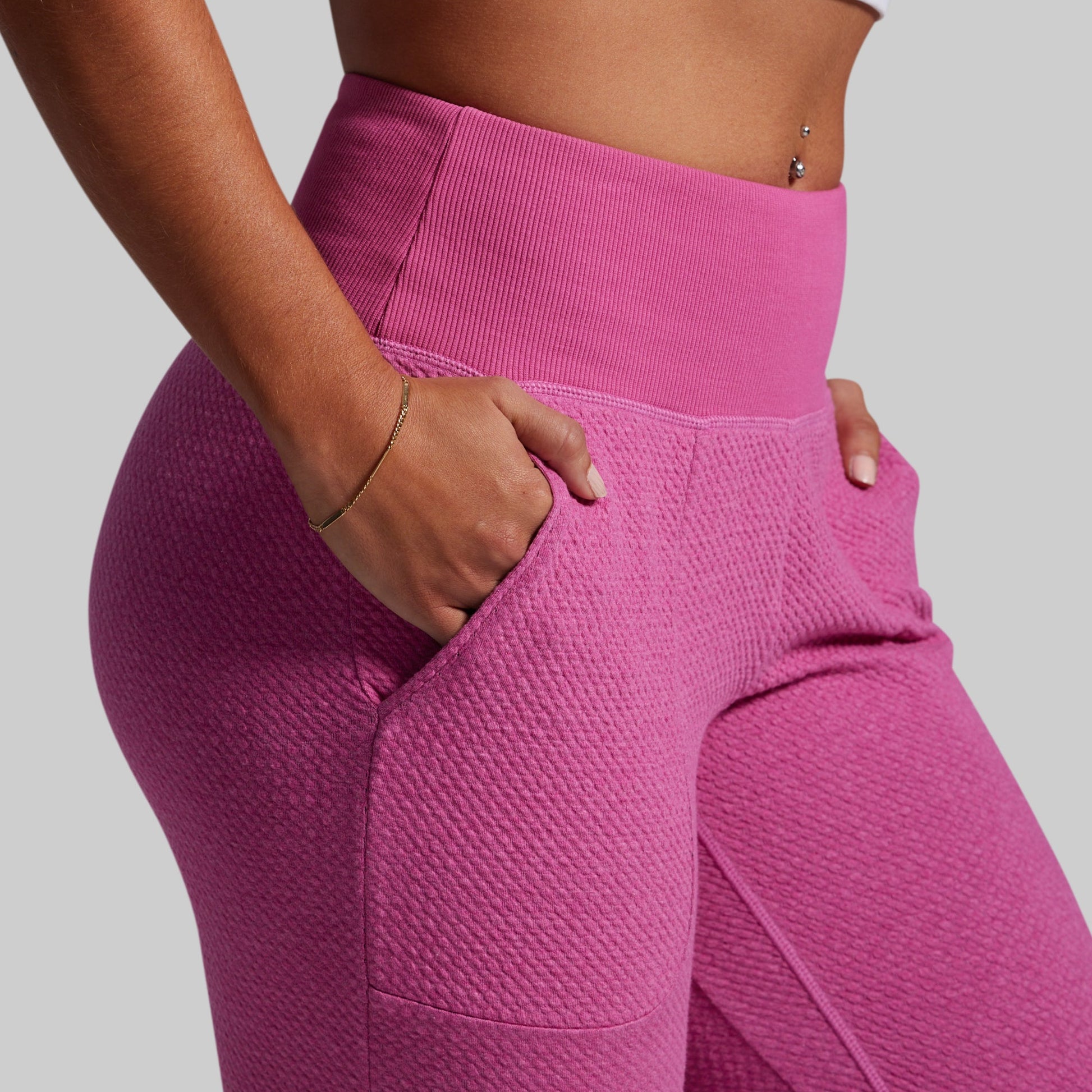 Person wearing pink textured leggings on a plain background