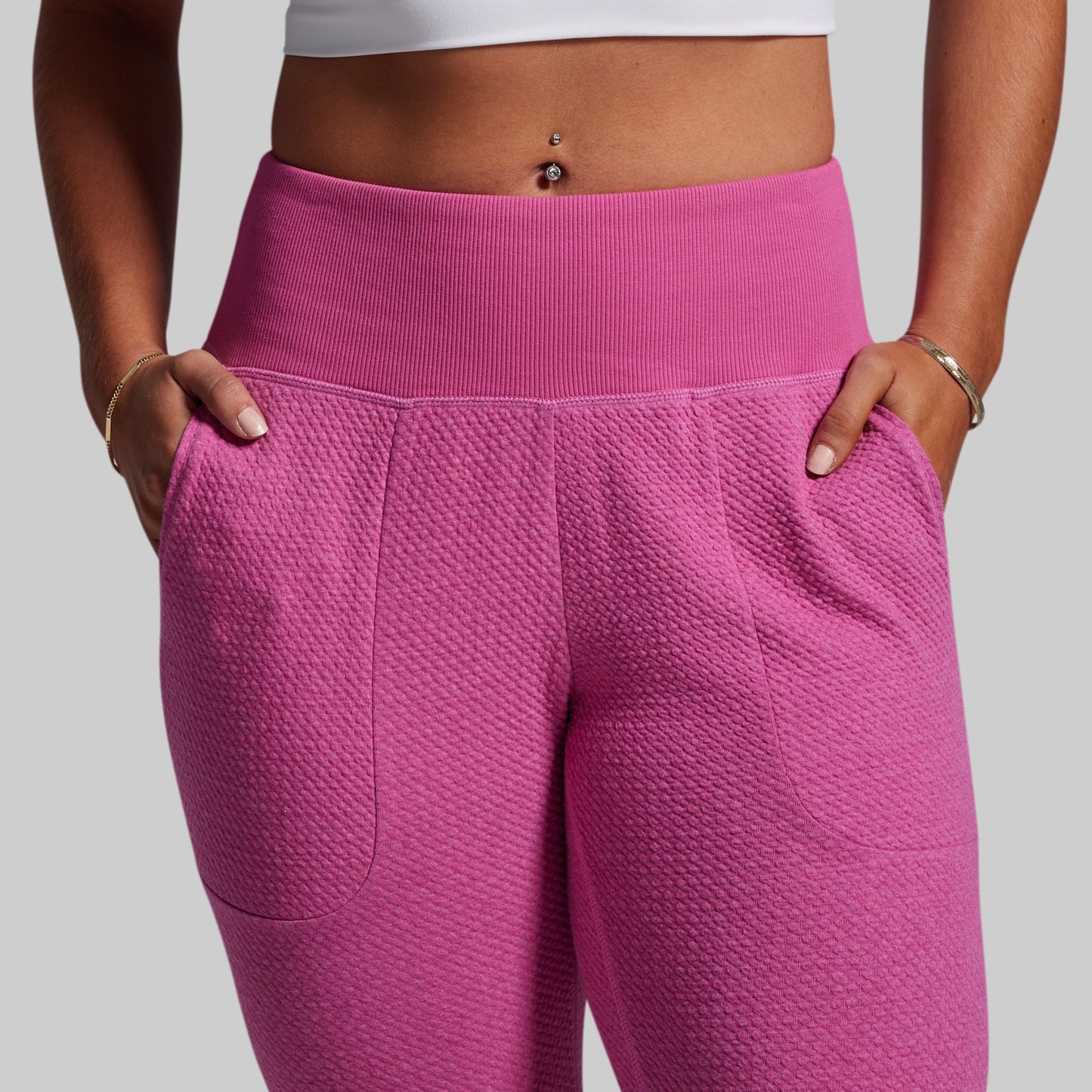 Person wearing pink textured leggings with a plain background