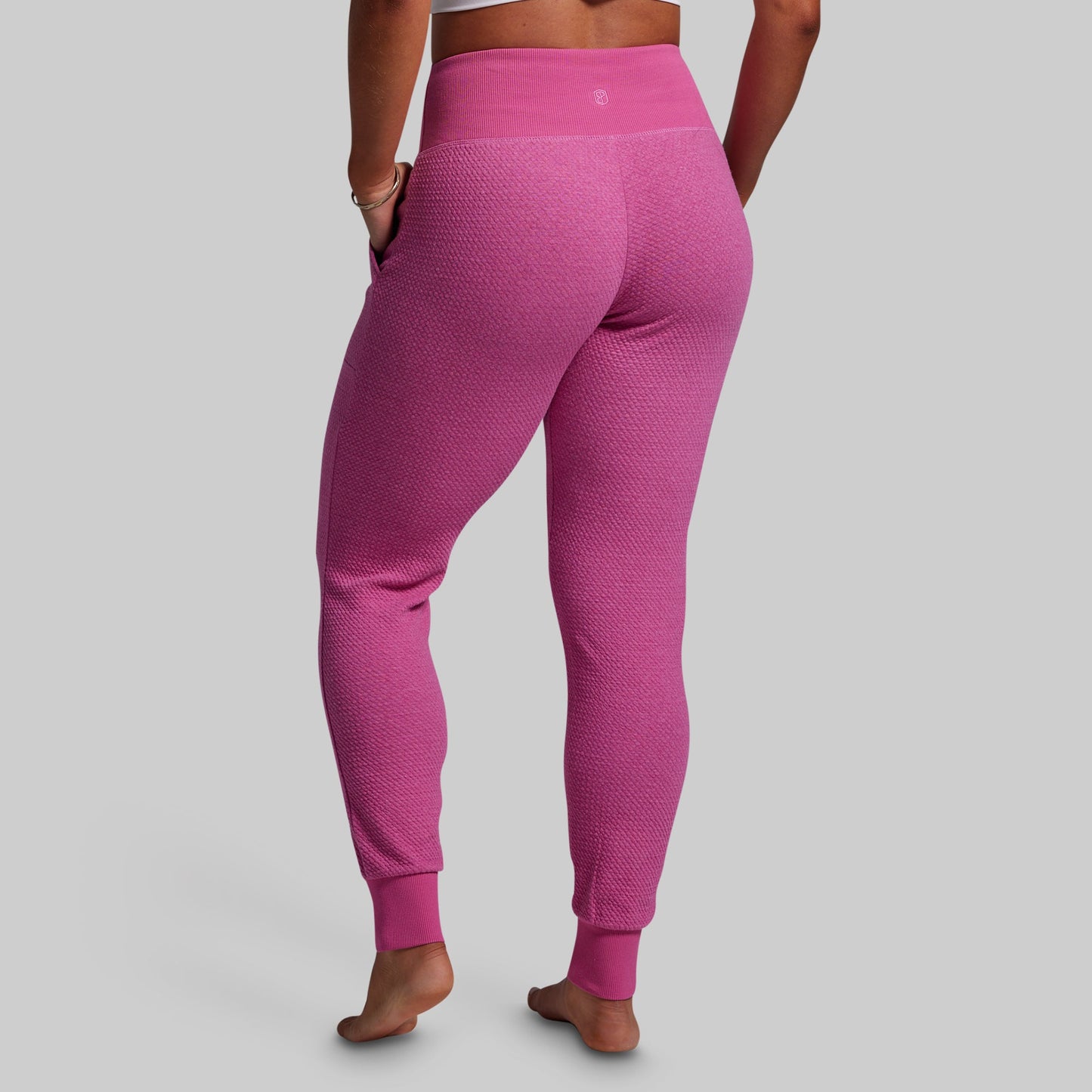 Pink textured leggings worn by a person on a gray background
