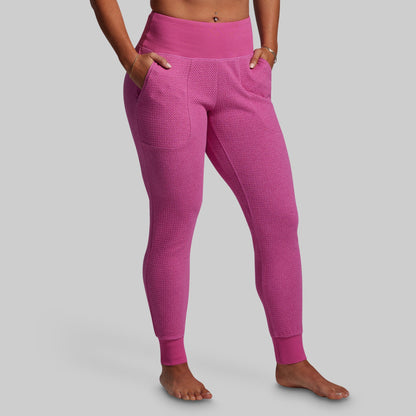 Person wearing bright pink textured leggings on a gray background