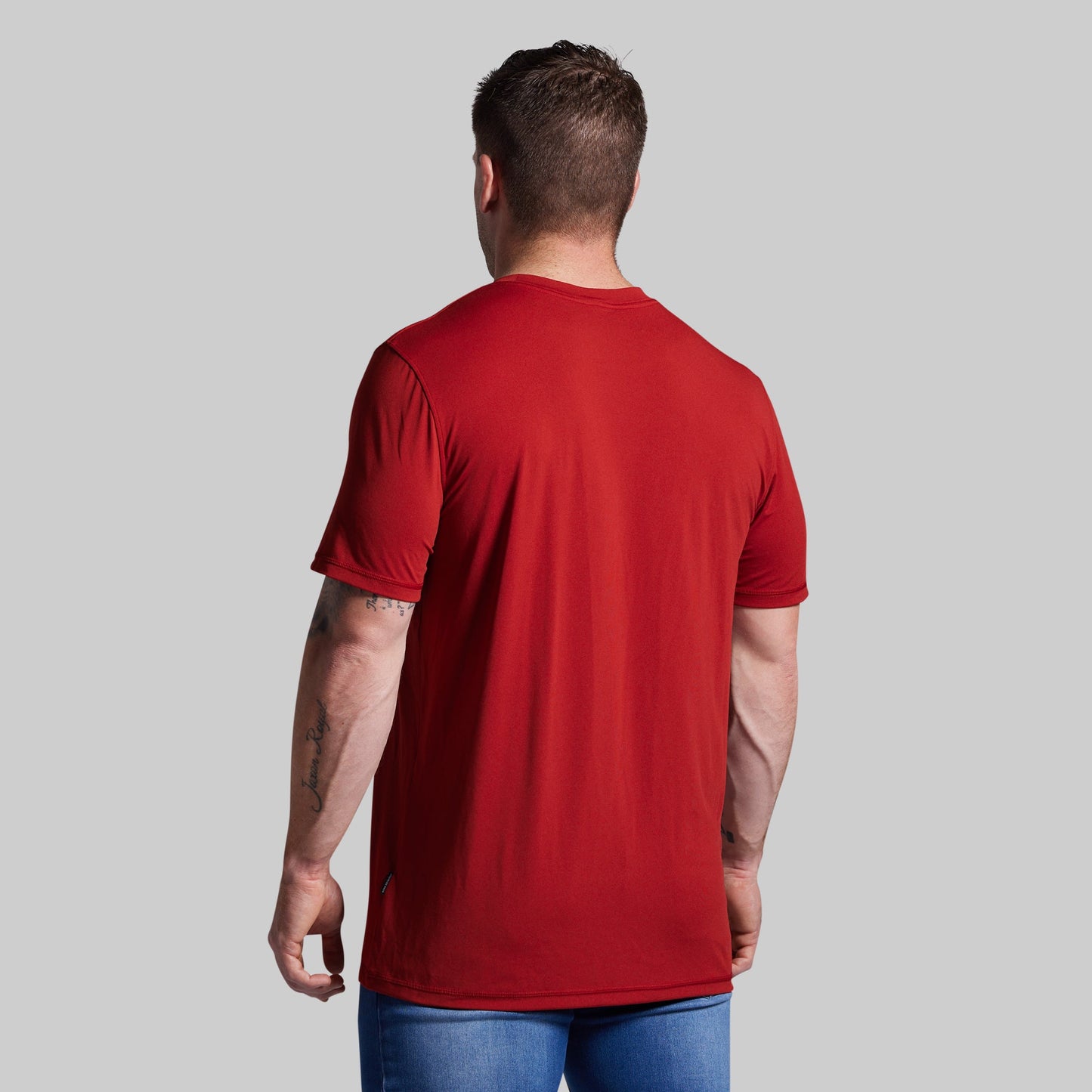 Man wearing a red t-shirt against a gray background
