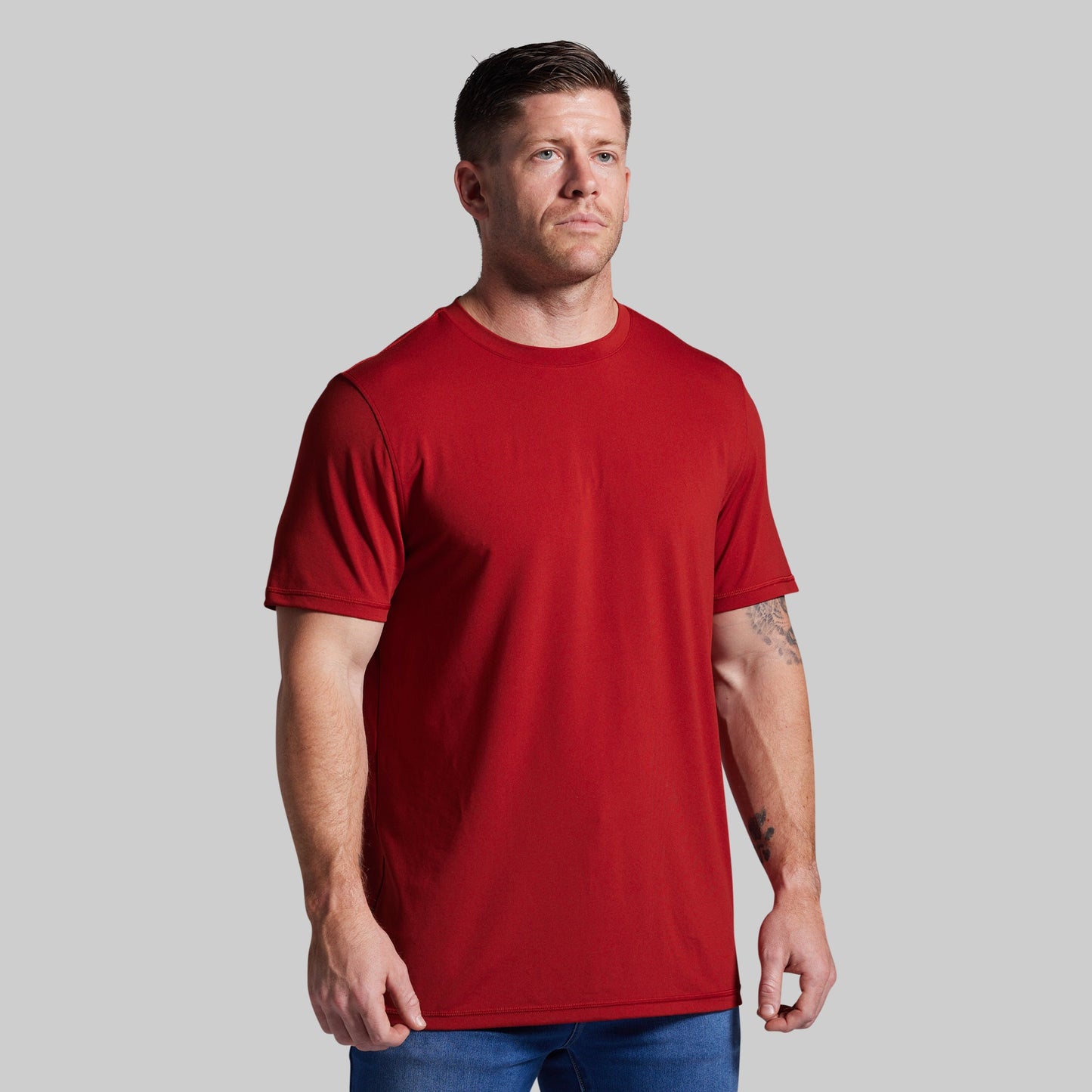 Man wearing a red t-shirt against a gray background