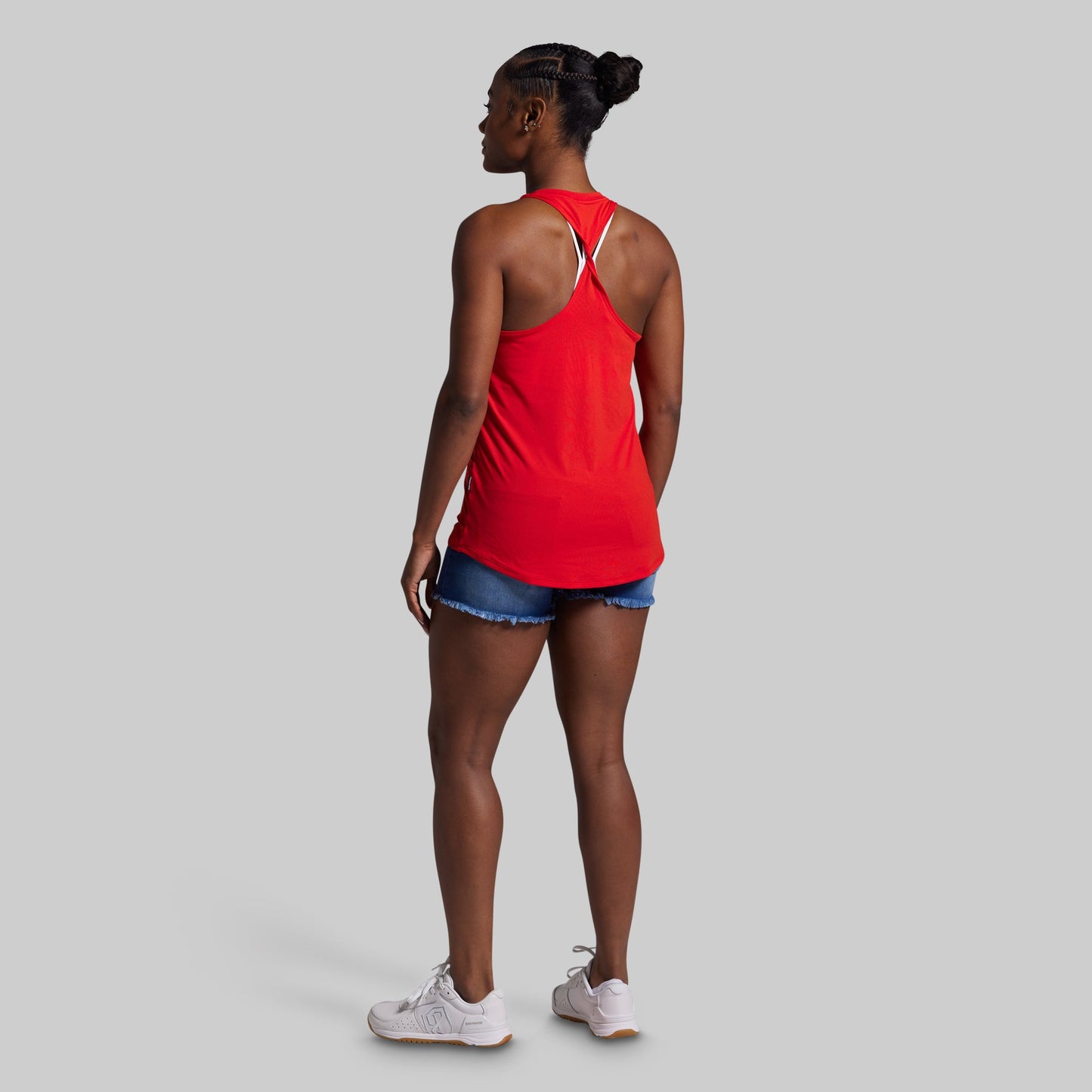 Person wearing a red tank top and denim shorts on a gray background