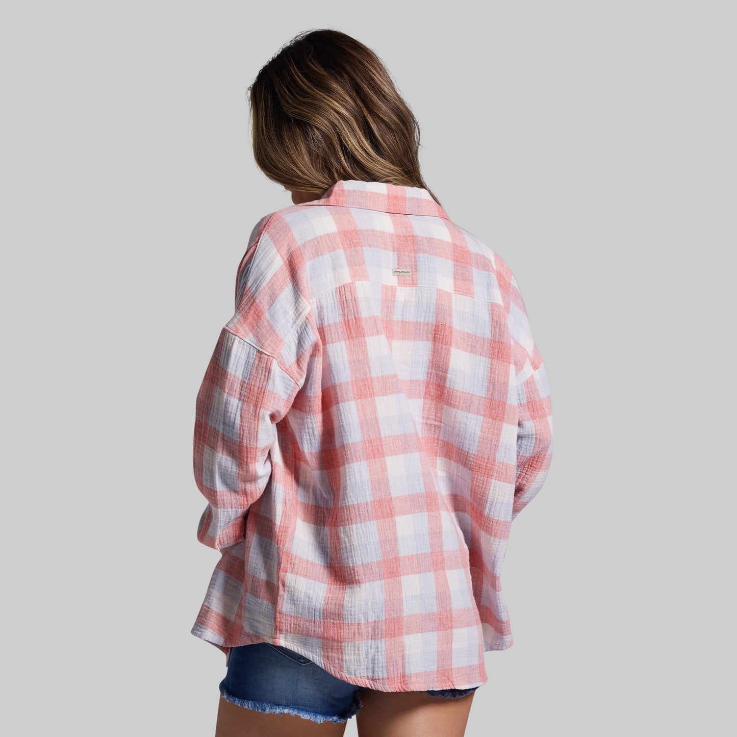 Person wearing a pink and white plaid shirt on a plain background