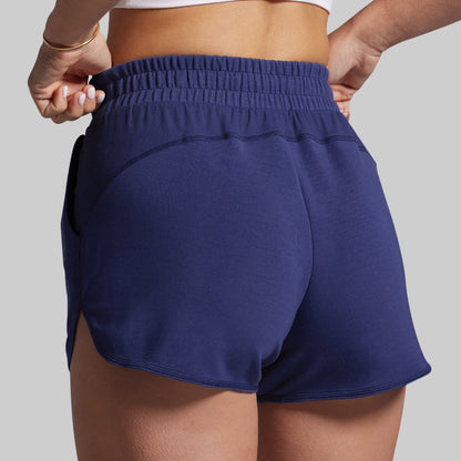 Navy blue athletic shorts worn by a person on a gray background